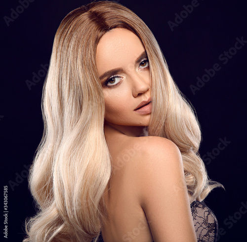 Ombre blond curly hair. Beauty fashion blonde woman portrait. Beautiful girl model with makeup, long healthy hairstyle posing isolated on studio black background.