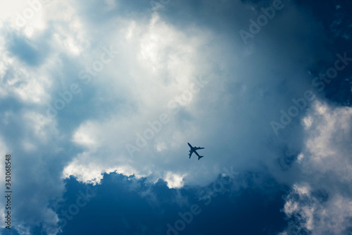 Airplane flying in the deep blue sky among clouds