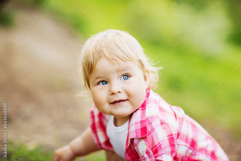 Pretty fair-haired blue-eyed toddler girl in pink plaid shirt, white t-shirt, blue denim jeans shorts and stylish red robber boots walking in the farm park with ducks and ducklings Pretty fair-haired blue-eyed toddler girl in pink plaid shirt, white t-shirt, blue denim jeans shorts and stylish red robber boots walking in the farm park with ducks and ducklings