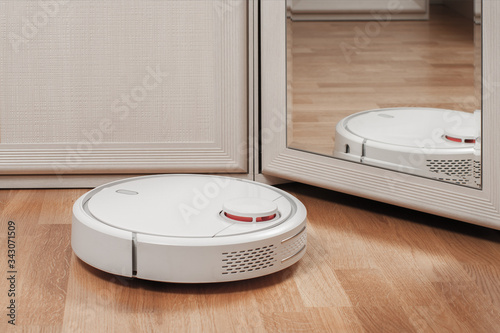 reflection of white robotic vacuum cleaners. modern smart appliance for cleaning house