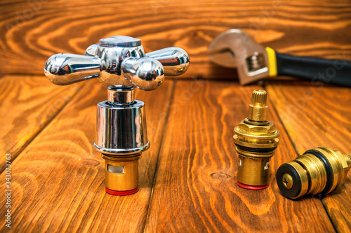 фотографія A cruciform hot and cold water main switch of spare parts on vintage wooden boar