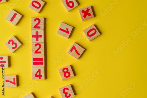 Wood numbers on a yellow background. Primary school, first grade. Mathematics. Two plus two equals four