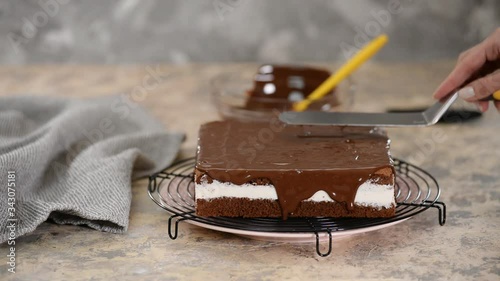 Chocolate glaze pouring on cake. The confectioner glazes a cake. photo