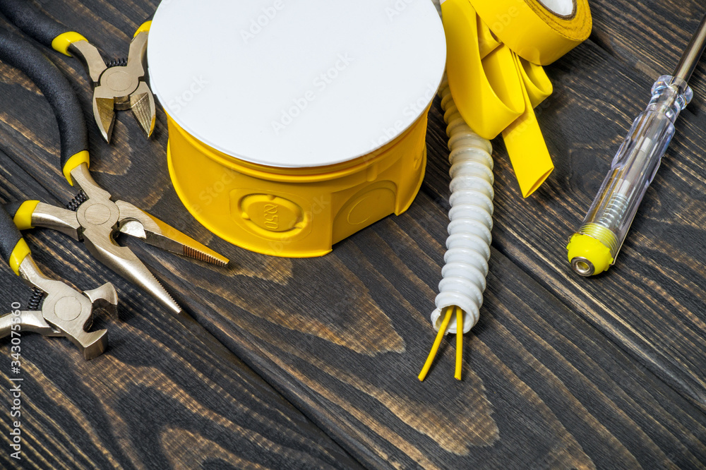 Yellow kit spare parts and tools for electrical prepared before repair on black wooden boards