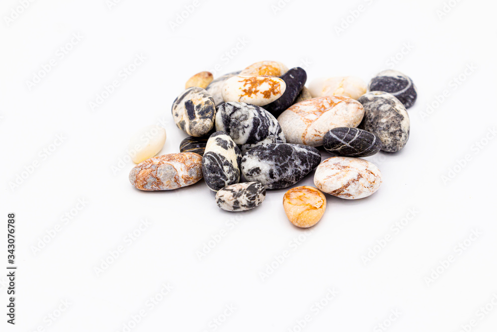 A set of pebbles stones lie in a pile with various patterns on a white background with a shadow. A set of pebbles stones lie in a pile with various patterns on a white background with a shadow.