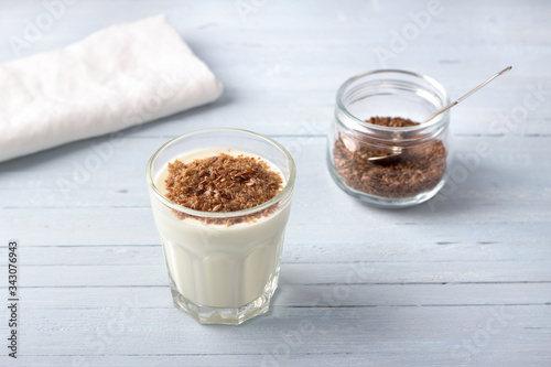 Simple healthy breakfast or snack. Natural yogurt with ground flax seeds in glasses on a light blue background