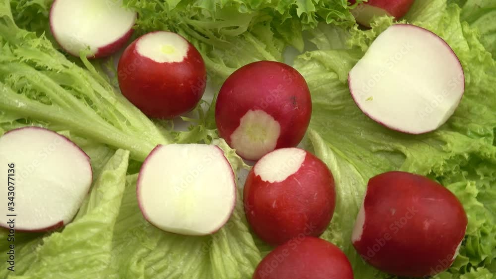 Whole radish and its' slices lay on the lettuce leaves Whole radish and its' slices lay on the lettuce leaves