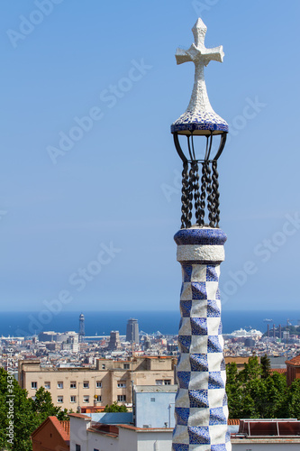BARCELONA, CATALONIA, SPAIN - MAY 21, 2015: Close-up shot of Gaudi's building mosaic tower crowned with typical four-armed cross in Park Guell against blue sky in Barcelona, Catalonia, Spain