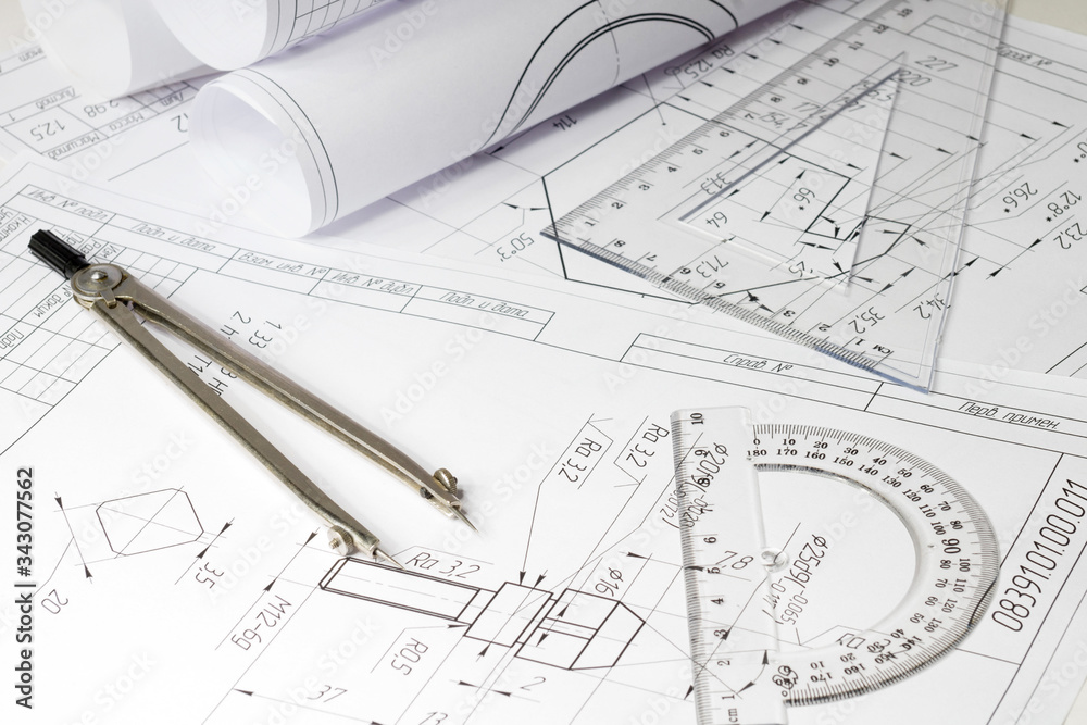 engineering drawings and rolls of drawings are on a white table, compasses, conveyor