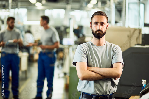 Portrait of confident factory worker standing with arms crossed.
