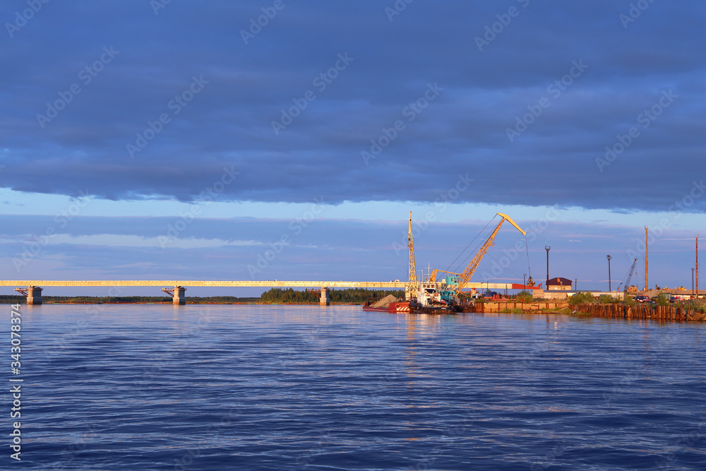 Bridge and boat with barge on the Nadym river in Siberia