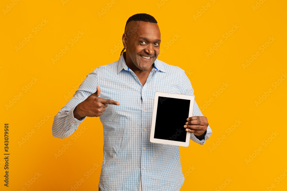 Middle aged black man pointing finger at blank digital tablet screen Middle aged black man pointing finger at blank digital tablet screen