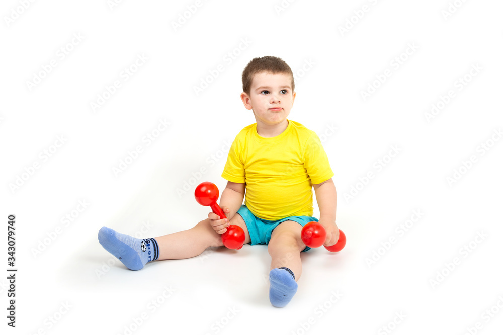 the happy boy is engaged in fitness, sports with red dumbbells the happy boy is engaged in fitness, sports with red dumbbells