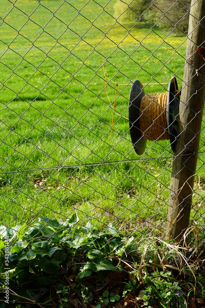 Foto de metal wire fence with a coil of electric wire fixed on a wooden ...