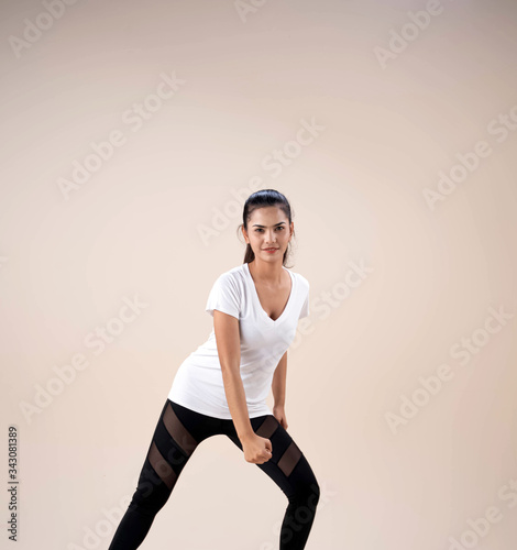 Young beautiful lady wearing sportwear,standing feet aparts kneel and put fist beside her legs,dance workout for exercise,with happy feeling