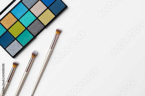 make up cosmetic palette on white background and brush, top view