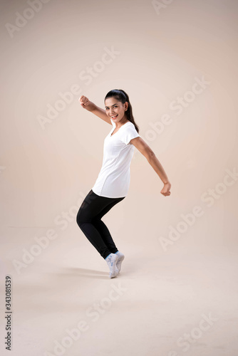 Young beautiful lady wearing sportwear,standing feet aparts kneel ,stepping,raise fists up and down little twisted,dance workout for exercise,with happy feeling