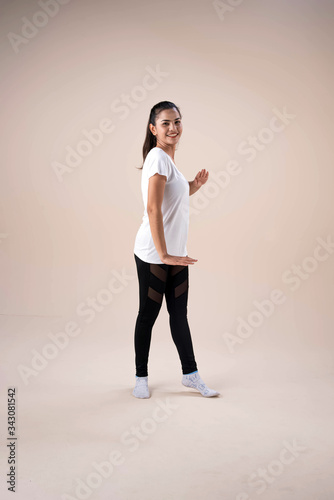 Young beautiful lady wearing sportwear,standing feet aparts kneel ,stepping,raise hands up and down little twisted,dance workout for exercise,with happy feeling