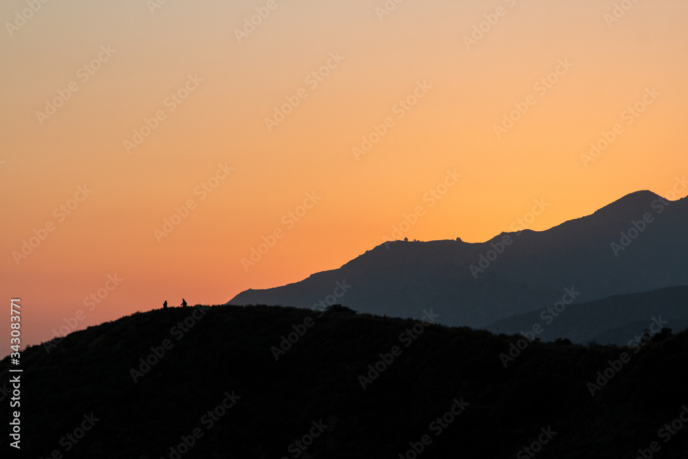 Obraz premium sunset mountain view, two silhouettes on a mountain
