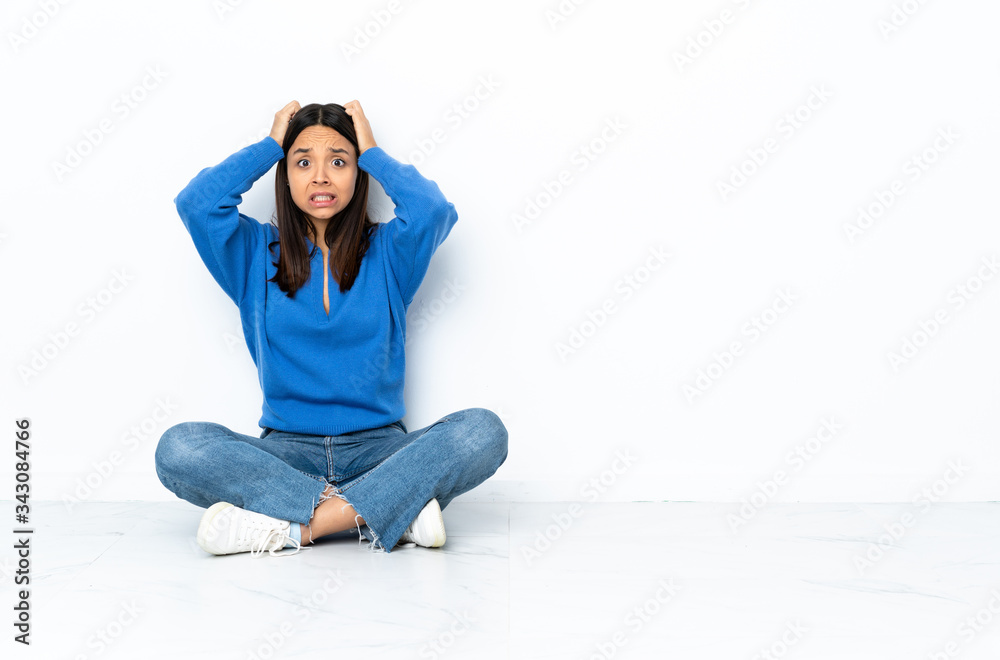 Young mixed race woman sitting on the floor isolated on white background doing nervous gesture Young mixed race woman sitting on the floor isolated on white background doing nervous gesture