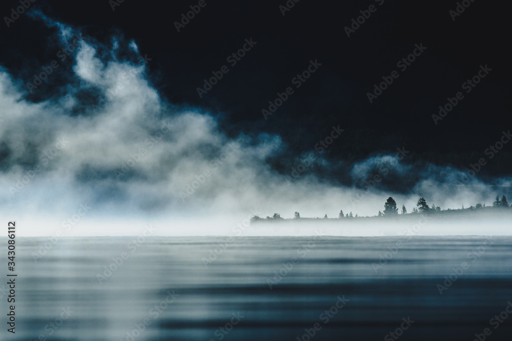 Dramatic view of a mountain lake in the cover of dense fog in the Ulagansky District of the Altai republic, Russia
