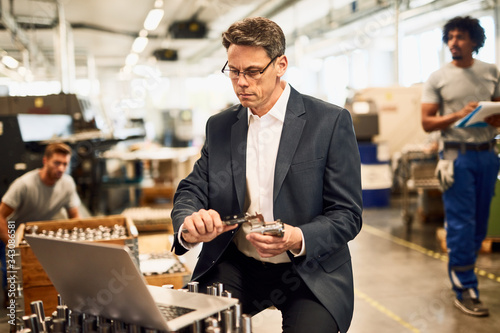 Billede på lærred Quality control inspector measuring steel bolt with a caliper in industrial building