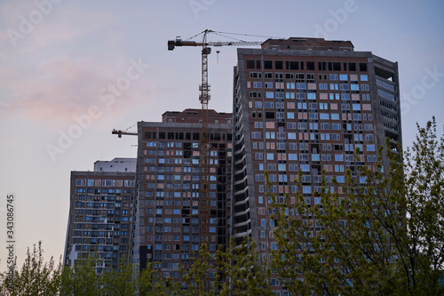 Unfinished office and residential building with a crane in Kyiv at sunset 
