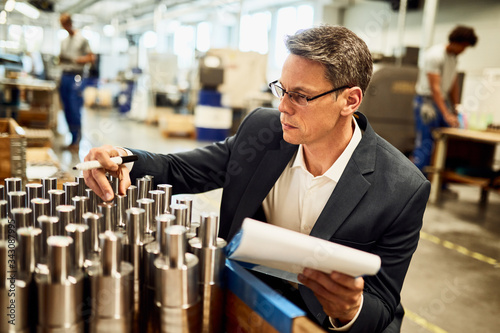 Quality control inspector examining manufactured steel cylinders in a a factory.