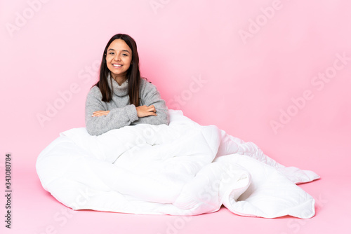 Young mixed race woman wearing pijama sitting on the floor with arms crossed and looking forward