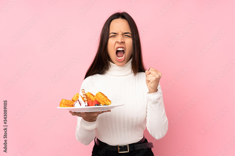 Young brunette woman holding waffles over isolated pink background frustrated by a bad situation Young brunette woman holding waffles over isolated pink background frustrated by a bad situation