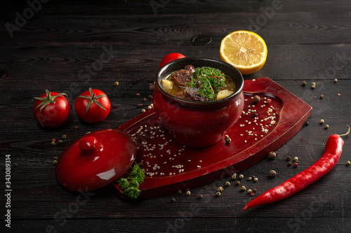 vegetable stew with potatoes and meat in a pot on a dark wooden background