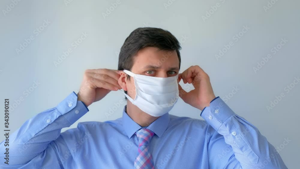 Man putting on protective medical mask on face, coronavirus pandemic. Man in shirt with tie, office worker on white background. Worldwide global COVID-19 epidemic. Fighting with 2019-ncov infection. Man putting on protective medical mask on face, coronavirus pandemic. Man in shirt with tie, office worker on white background. Worldwide global COVID-19 epidemic. Fighting with 2019-ncov infection.