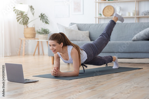 Sporty Girl Exercising at Home, using laptop