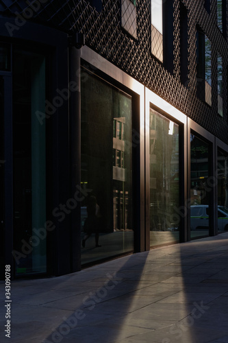 Low yellow sunlight reflecting off building window onto pavement towards viewer