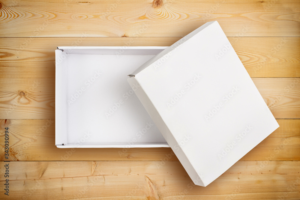 Fototapeta premium Opened empty cardboard box with cover on wooden background.