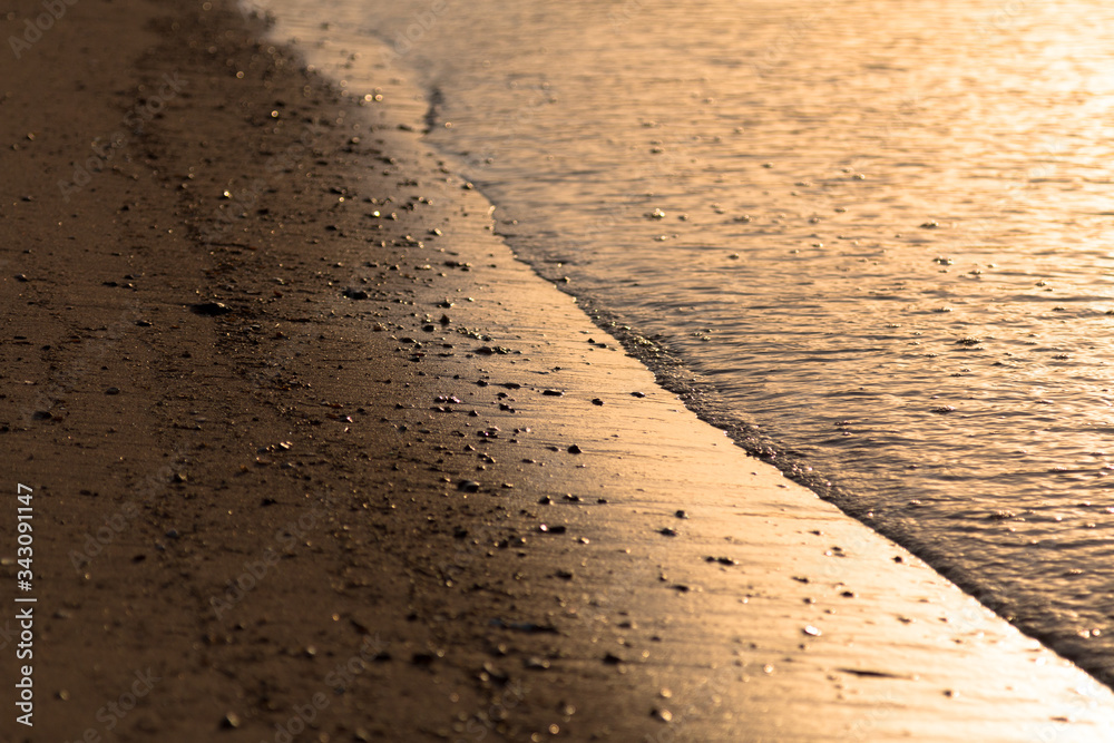 Closeup on sea waves in golden hour, several small stones and beautiful water line Closeup on sea waves in golden hour, several small stones and beautiful water line