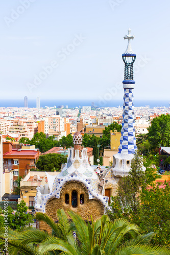 BARCELONA, CATALONIA, SPAIN - MAY 21, 2015: Gaudi's building with mosaic tower with typical four-armed cross in Park Guell against blue sky in Barcelona, Catalonia, Spain