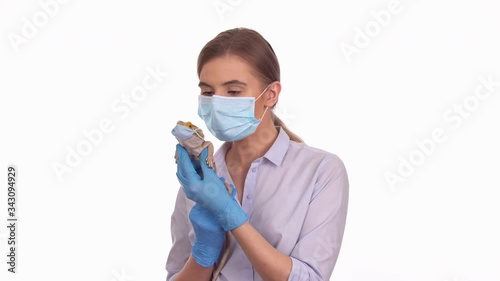 Young lady holding her pet bearded agama lizard wearing sterile medical mask, funny COVID-19 quarantine concept