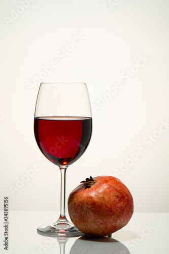 Glass with red wine and pomegranate on a light background