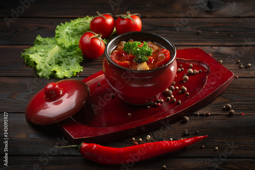 vegetable stew with potatoes and tomatoes in a pot on a dark wooden background