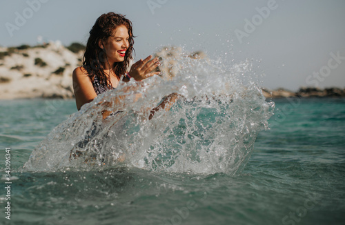 Young woman walking in the warm sea water at summer