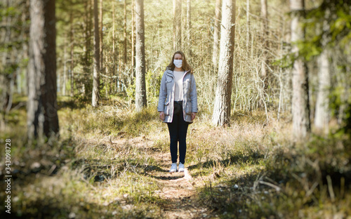 Woman in medical mask in the middle of the forest.