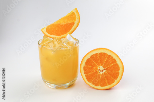 Fresh yellow orange juice in glass with orange slice and ice cube on white background