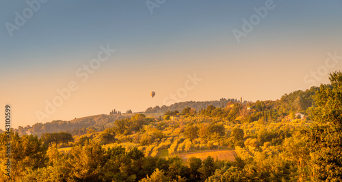 Summer sunrise over the fields and rolling hills with air balloon. Travel destination Chianti, Tuscany