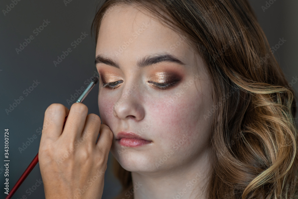Makeup artist paints eyelids on a model girl. Makeup artist paints eyelids on a model girl.