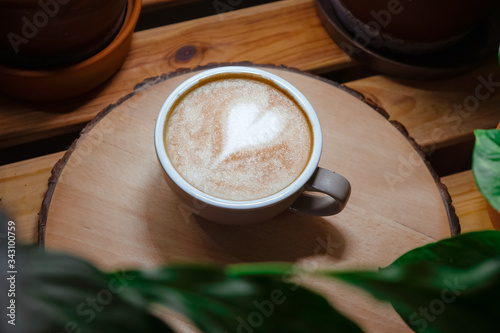 Coffee latte from above view with heart foam art and plants around lay on wooden tray 