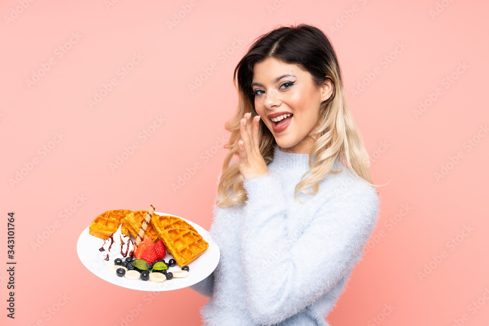 Teenager girl holding waffles on isolated pink background whispering something Teenager girl holding waffles on isolated pink background whispering something