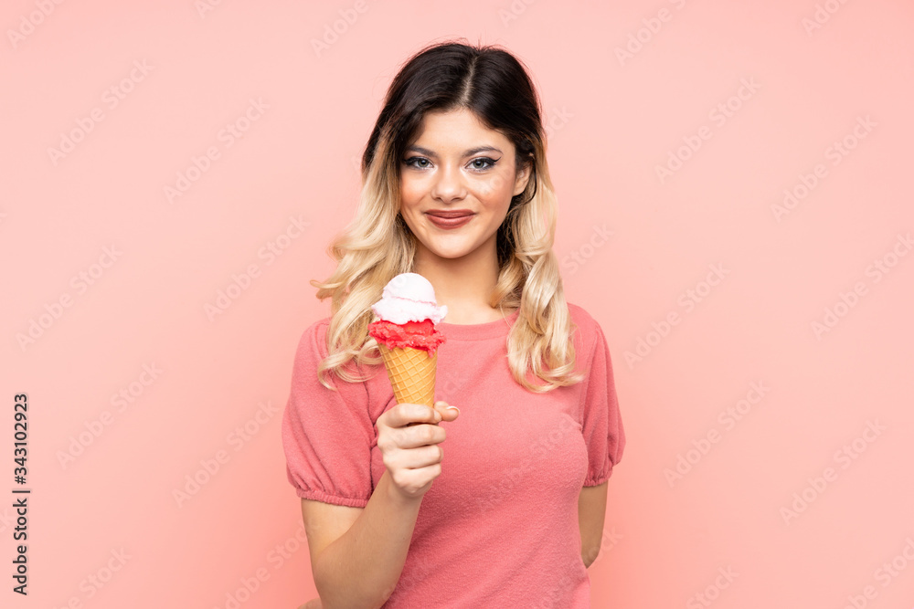 Teenager girl holding a cornet ice cream isolated on pink background with happy expression Teenager girl holding a cornet ice cream isolated on pink background with happy expression