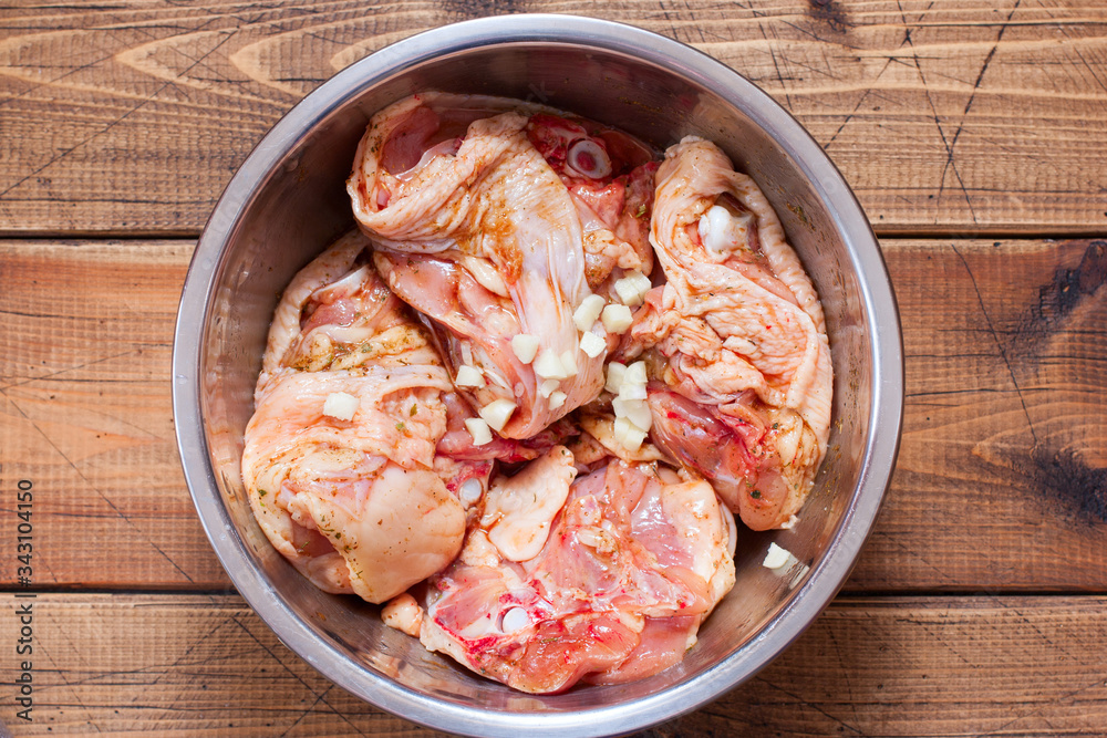 Step by step cooking of baked chicken with vegetables, step 2 - marinating chicken thighs, selective focus Step by step cooking of baked chicken with vegetables, step 2 - marinating chicken thighs, selective focus