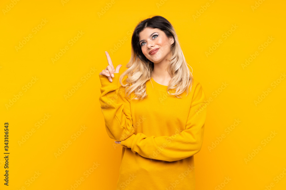 Teenager girl isolated on yellow background showing and lifting a finger in sign of the best Teenager girl isolated on yellow background showing and lifting a finger in sign of the best